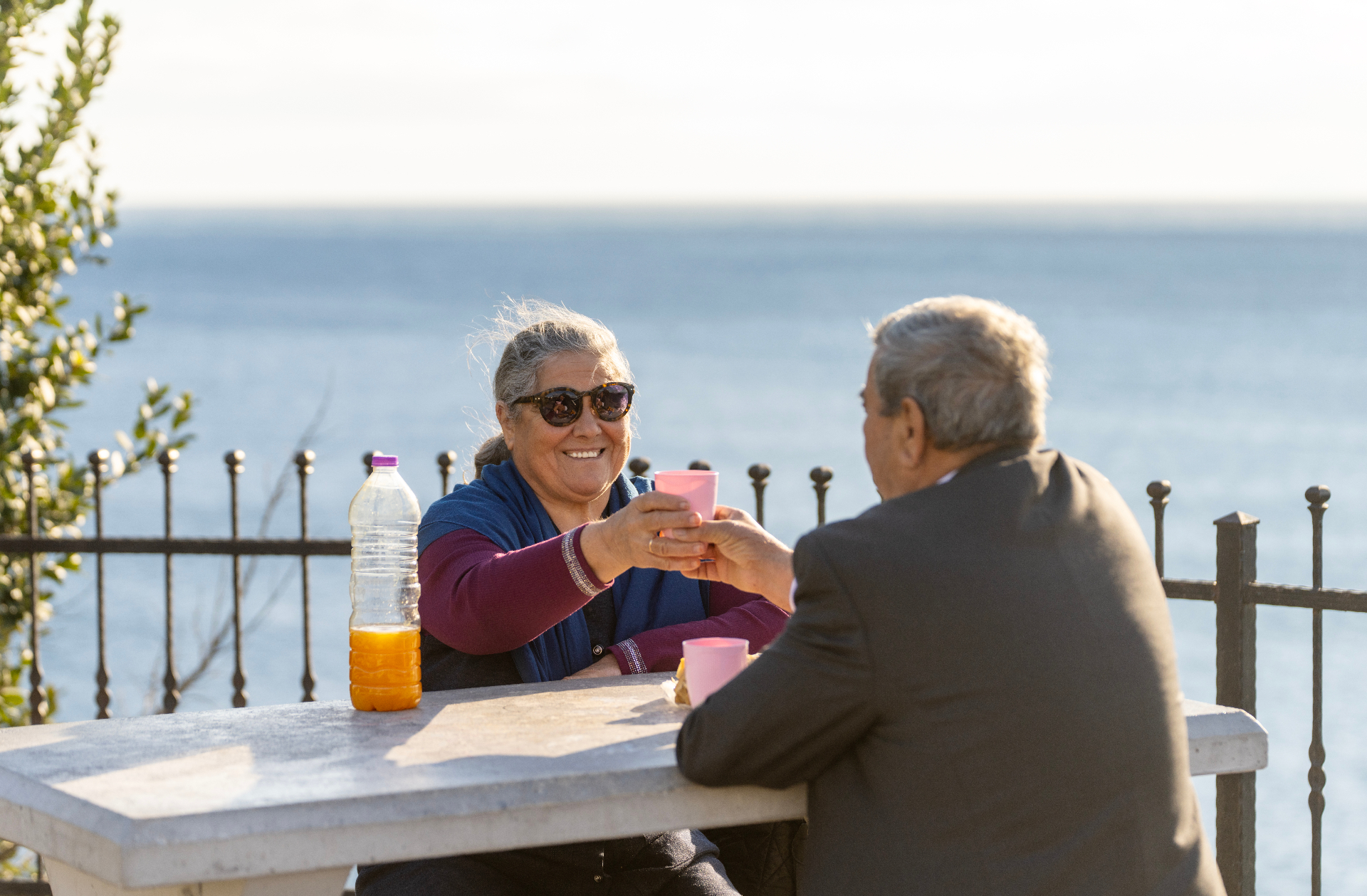 Two senior friends laughing over coffee with an ocean view